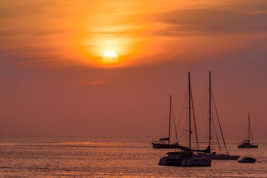 Deniz sahilinde gün batımı geçmişli bir tekne silueti. Phuket Adası, Tayland 'da deniz kenarında gün batımı anı