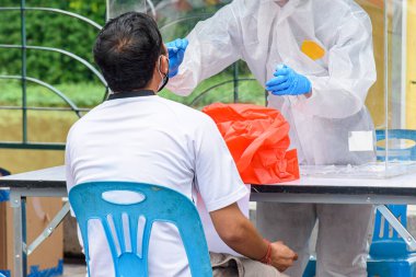 Koruyucu giysili sağlık görevlileri Tayland 'ın Chiang Mai şehrindeki insanlar için COVID-19 testi yapıyorlar.