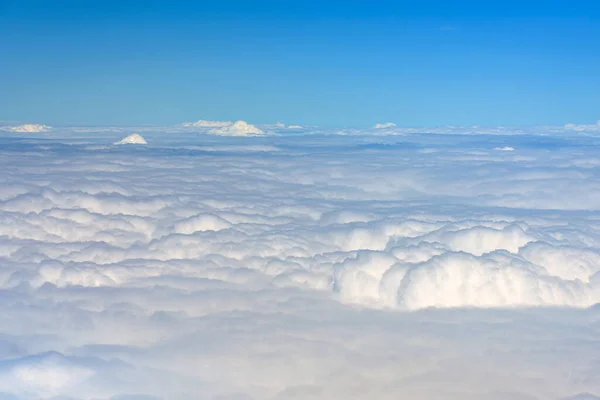 Clouds against blue sky view through an airplane window for a background. Above the clouds, flying in the air