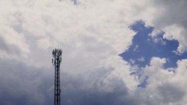 4K zaman atlaması, gri ve beyaz yuvarlanan kabarık bulutlar gökyüzünde telekomünikasyon kuleleriyle birlikte. Gri bulutlarda kule sinyalinin yer değiştiren arkaplan görüntüsü