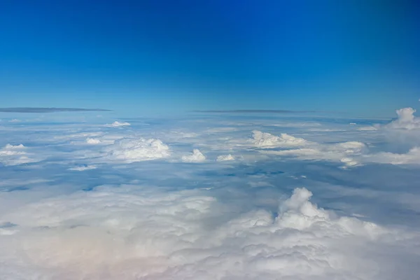 Clouds against blue sky view through an airplane window for a background. Above the clouds, flying in the air