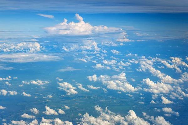 Clouds against blue sky view through an airplane window for a background. Above the clouds, flying in the air