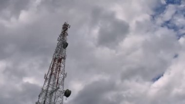 4K zaman atlaması, gri ve beyaz yuvarlanan kabarık bulutlar gökyüzünde telekomünikasyon kuleleriyle birlikte. Gri bulutlarda kule sinyalinin yer değiştiren arkaplan görüntüsü