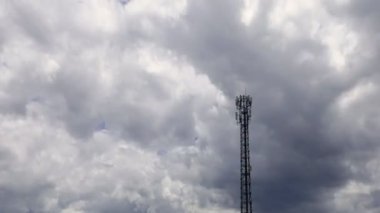 4K zaman atlaması, gri ve beyaz yuvarlanan kabarık bulutlar gökyüzünde telekomünikasyon kuleleriyle birlikte. Gri bulutlarda kule sinyalinin yer değiştiren arkaplan görüntüsü