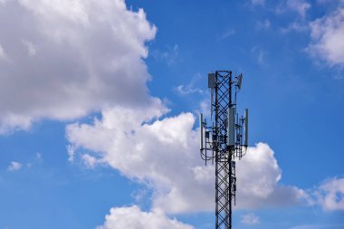 Mavi gökyüzü arka planında bulutları olan telekomünikasyon kuleleri. Mavi gökyüzü beyaz bulutlu arka planda kule sinyali