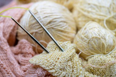 Örgü iğneleri, iplik izleri, örgü kumaşlar, ev işi. Yakın çekim, seçici odaklanma