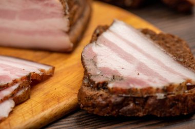 Tahta bir kesme tahtasındaki tahıllı ekmeğin üzerinde füme göğüs eti dilimlenmiş sandviç. Yakın çekim, seçici odaklanma.