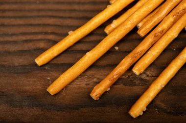 Ahşap masaya saçılmış tuzlu ekmek şeritleri. Yakın çekim, seçici odaklanma.