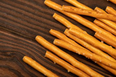 Ahşap masaya saçılmış tuzlu ekmek şeritleri. Yakın çekim, seçici odaklanma.