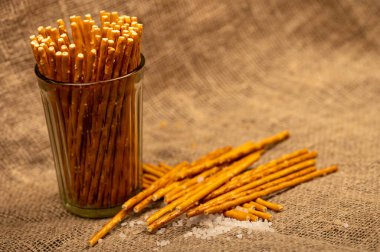 Cam bir fincanda tuzlu ekmek şeritleri ve kaba ev yapımı kumaş üzerine serpilmiş. Yakın çekim, seçici odaklanma.