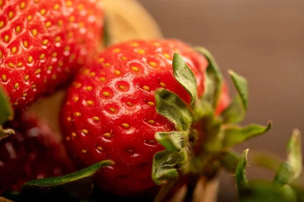 Tahta bir masada hasır sepetin içinde taze kırmızı çilekler. Hasat. Yakın çekim, seçici odaklanma.
