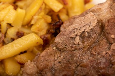 Ev yapımı kızarmış patates ve beyaz tabakta büyük bir parça et. Yakın plan..