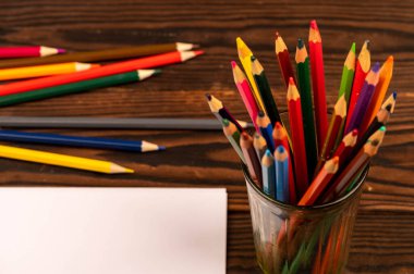 Ahşap bir masada renkli kalemler ve beyaz kağıtlar. Seçici odaklanmayı kapat.