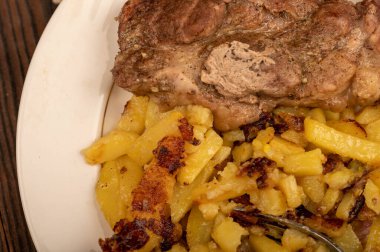 Ev yapımı kızarmış patates ve beyaz tabakta büyük bir parça et. Yakın plan..