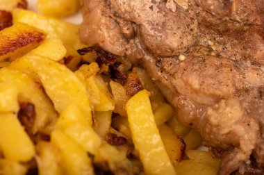 Ev yapımı kızarmış patates ve beyaz tabakta büyük bir parça et. Yakın plan..