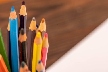 Ahşap bir masada renkli kalemler ve beyaz kağıtlar. Seçici odaklanmayı kapat.