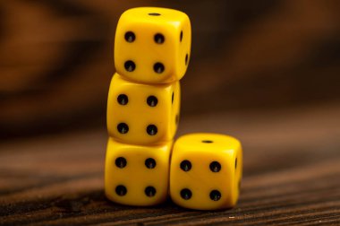 Tahta masaya saçılmış sarı zarlar. Yakın plan, seçici odaklanma. Tahta oyunlarının vazgeçilmez bir özelliği.