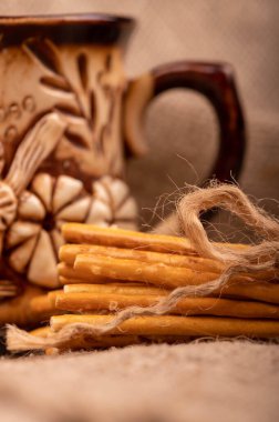 İple bağlanmış tuzlu ekmek çubukları ve çay için bir toprak kap. Seçici Odaklamayı Kapat