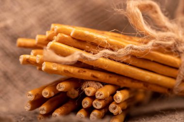 Kabataslak desenli ev yapımı bir kumaşın arka planında sicimle bağlanmış tuzu olan ekmek çubukları. Seçici Odaklamayı Kapat