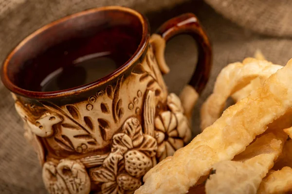Fried bread sticks with salt and a ceramic mug, close-up, selective focus