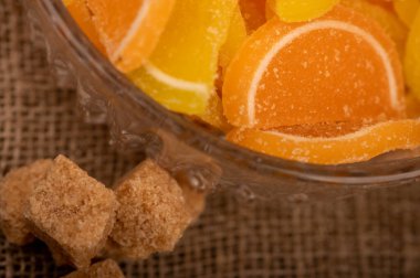 Cam bir vazoda çok renkli marmelat dilimleri ve kahverengi kamış şekeri, yakın plan, seçici odaklanma.