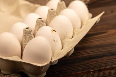 Beyaz kartondan yapılmış tepside beyaz tavuk yumurtaları, yakın plan seçici odak.