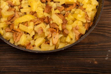 Tahta bir masada mantarlı kızartma tavasında patates kızartması. Geleneksel köy yemeği.