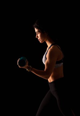 Genç bayan sporcu kol kaslarını güçlendirmek için ağırlık çalışması yapıyor. Sporcu dinleniyor.