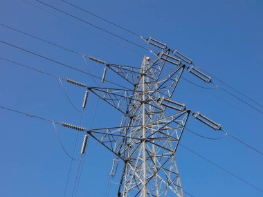 Elektrik enerjisi taşıyan bakır kabloları destekleyen metal kuleler, mavi gökyüzündeki kuleler: Yüksek voltaj kuleleri, elektrik kablolarını desteklemek için mühendislik çalışmaları