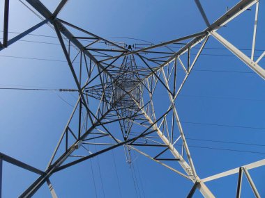 Elektrik enerjisi taşıyan bakır kabloları destekleyen metal kuleler, mavi gökyüzündeki kuleler: Yüksek voltaj kuleleri, elektrik kablolarını desteklemek için mühendislik çalışmaları