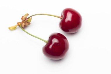 Vitamin ve lezzetli tatlarla dolu beyaz bir zemin üzerinde küçük kırmızı kiraz seti, çiğ ya da tatlı yemek için ideal..