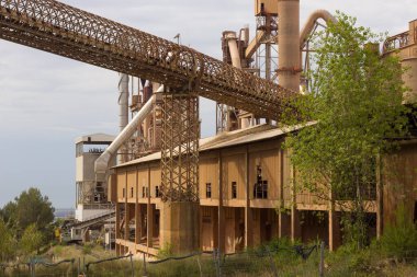 Birkaç yıl önce kapatılmış çimento fabrikası, siloları ve fırınları bomboş duruyor. Barselona yakınlarındaki dağlarda çimento fabrikası..