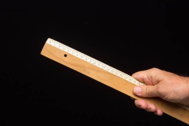 Ahşap cetvel, ölçü almak ve teknik çizimler yapmak için klasik, siyah arka planda. # Bir insanın elinde hükümdar #