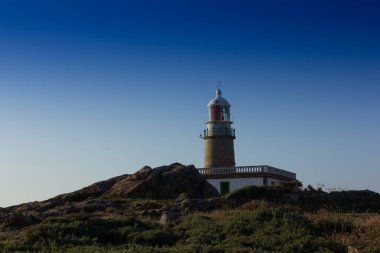 Atlantik Okyanusu 'ndaki Corrubedo deniz feneri, Galiçya, İspanya. Güvenli navigasyon için kayalıkların tepesindeki deniz feneri..