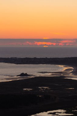 Atlantik Okyanusu üzerinde gün batımında kırmızımsı ve turuncu renkler. Denizin üzerinde güneş batıyor.