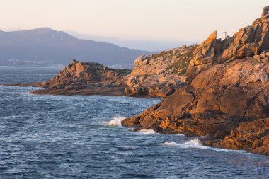 Yaz mevsiminde gün batımında mavi deniz ve kayalık sahil. Açık gün, mavi gökyüzü