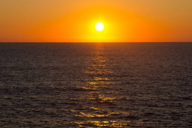 Atlantik Okyanusu üzerinde gün batımında kırmızımsı ve turuncu renkler. Denizin üzerinde güneş batıyor.