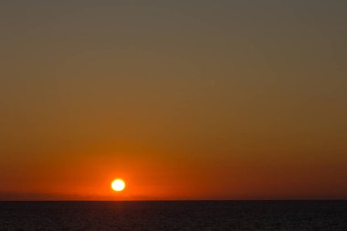 Atlantik Okyanusu üzerinde gün batımında kırmızımsı ve turuncu renkler. Denizin üzerinde güneş batıyor.