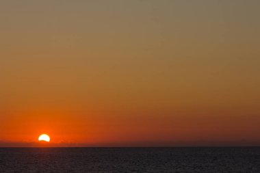 Atlantik Okyanusu üzerinde gün batımında kırmızımsı ve turuncu renkler. Denizin üzerinde güneş batıyor.