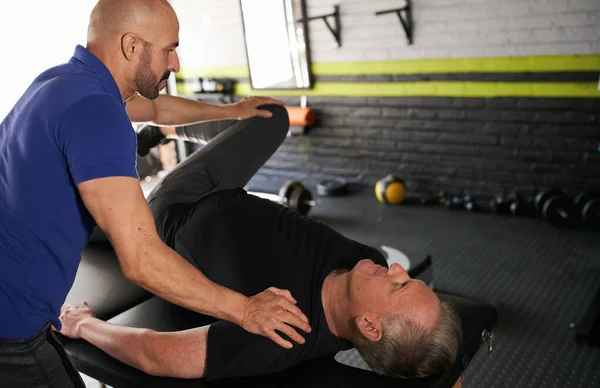 Männlicher Personal Trainer Und Physiotherapeut Unterstützt Reife Männer Bei Der Stockbild