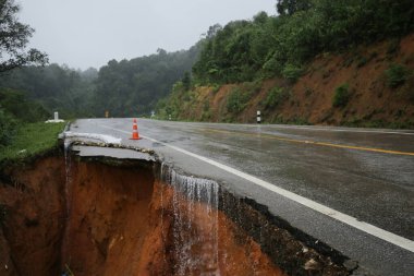 Şiddetli yağmurların yol açtığı heyelan, bozuk yol asfaltına neden olur. Sokakta yıkılmış çimento. Toprak kaymasından çıkan çatlak yol sağanak yağış yüzünden mahvoldu.