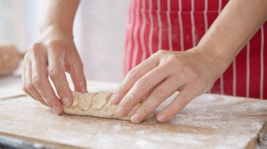 Kırmızı önlüklü bir kadın tarafından yapılan ev yapımı tahıl hamurundan tam buğday ekmeği. Bol taneli sağlıklı hamur işi..