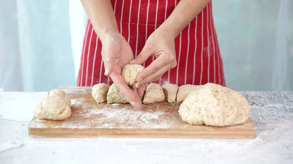 Whole wheat bread from homemade whole grain dough made by woman with red apron. Healthy pastry with many grains.