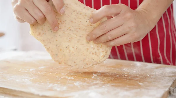 Whole wheat bread from homemade whole grain dough made by woman with red apron. Healthy pastry with many grains.