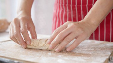 Kırmızı önlüklü bir kadın tarafından yapılan ev yapımı tahıl hamurundan tam buğday ekmeği. Bol taneli sağlıklı hamur işi..