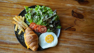 Peynirli vejetaryen kruvasan ve patates kızartması ve sebzeli sahanda yumurta. Sağlıklı Avrupa kahvaltısı