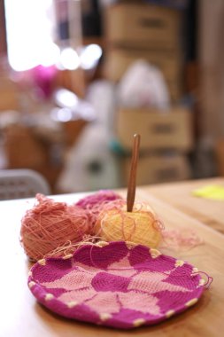 El sanatları okulunun stüdyosunda olduğu kadar gruptaki örgü ipliği de arka planda. İğneler el yapımı hobi için masanın üzerinde. Pamuklu iplikle örgü iplik torbası..