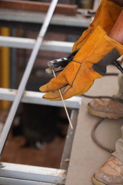 Kaynak yapmak için Engieer Güvenlik ve fabrikada çalışan sert donanım hattı üretim hatları için. Sarı Çelik Kaynak Güvenlik Eldivenleri uzun demir parmaklıklar üzerinde zemin inşa etmek için.