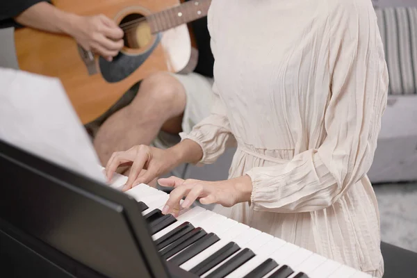 Adult women plays electronic piano with note sheet. Newby pianist practicing and learning how to play song.