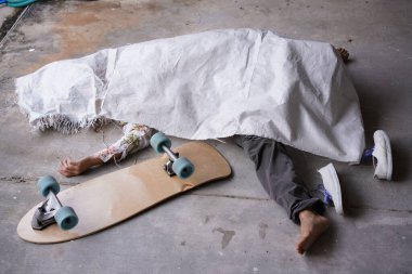 Ölü adam beyaz bir torbaya ya da kazadan ya da kurbanın evinde öldürülmekten dolayı örtülmüş bir cesede uzandı. Covid-19 hastalığı düşük sağlık hizmetlerinden bir insanı alıp götürdü. Sörf tahtası kazası.